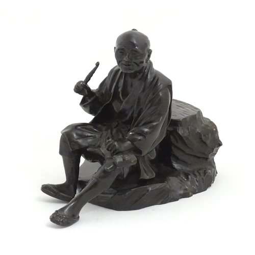 1148 - A Japanese cast sculpture modelled as a seated man on a rock smoking a kiseru pipe. Approx. 9 1/2