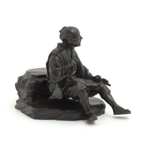 1148 - A Japanese cast sculpture modelled as a seated man on a rock smoking a kiseru pipe. Approx. 9 1/2