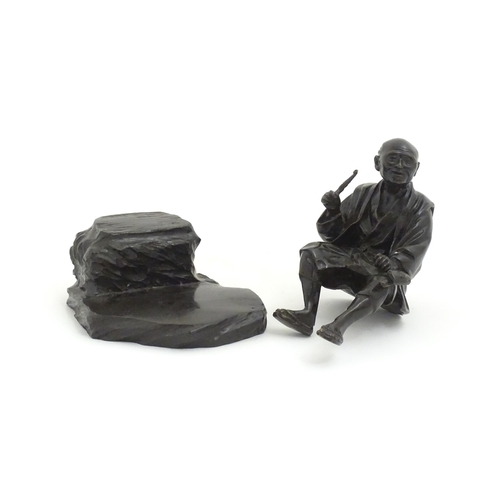 1148 - A Japanese cast sculpture modelled as a seated man on a rock smoking a kiseru pipe. Approx. 9 1/2