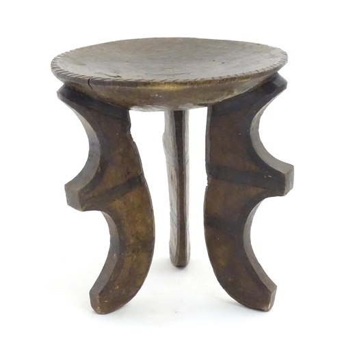 1187 - Ethnographic / Native / Tribal: A three legged African stool with carved detail. Approx. 19 1/2