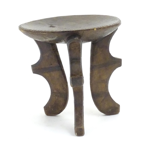 1187 - Ethnographic / Native / Tribal: A three legged African stool with carved detail. Approx. 19 1/2