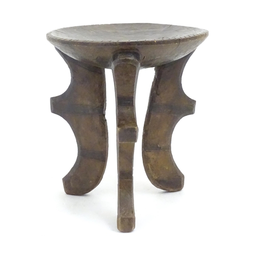 1187 - Ethnographic / Native / Tribal: A three legged African stool with carved detail. Approx. 19 1/2