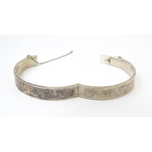 727 - A silver bracelet of bangle form with engraved acanthus scroll decoration, hallmarked Chester 1952. ... 