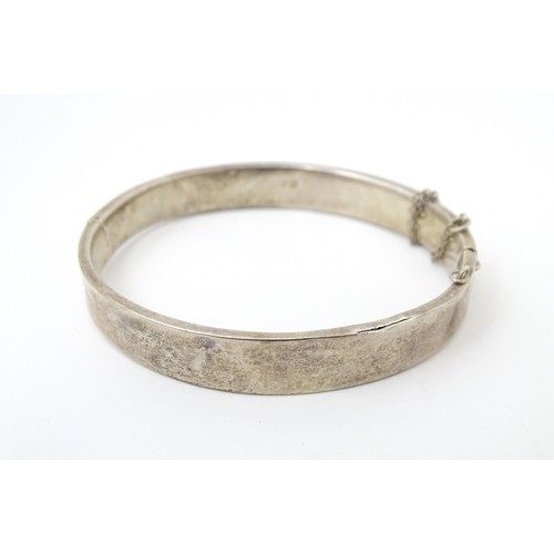 727 - A silver bracelet of bangle form with engraved acanthus scroll decoration, hallmarked Chester 1952. ... 