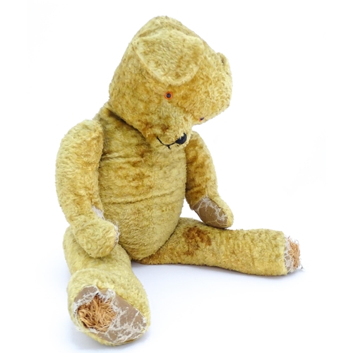 1426 - Toy: A large 20thC straw filled teddy bear with a stitched nose and mouth, and articulated limbs. Ap... 