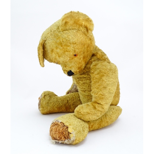 1426 - Toy: A large 20thC straw filled teddy bear with a stitched nose and mouth, and articulated limbs. Ap... 