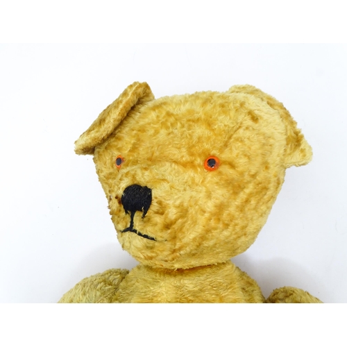 1426 - Toy: A large 20thC straw filled teddy bear with a stitched nose and mouth, and articulated limbs. Ap... 