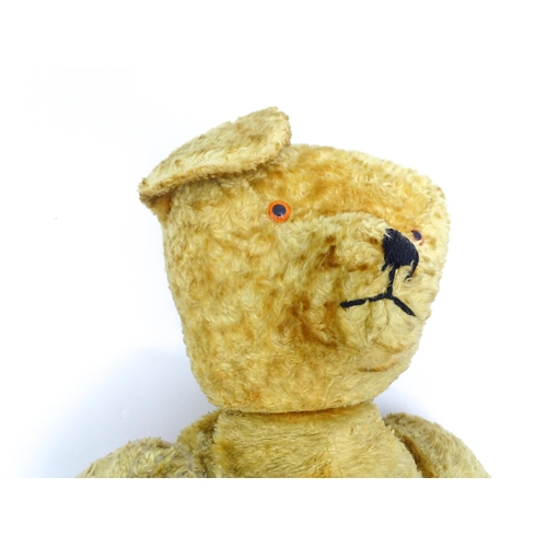 1426 - Toy: A large 20thC straw filled teddy bear with a stitched nose and mouth, and articulated limbs. Ap... 