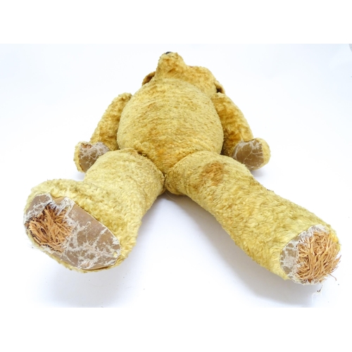 1426 - Toy: A large 20thC straw filled teddy bear with a stitched nose and mouth, and articulated limbs. Ap... 