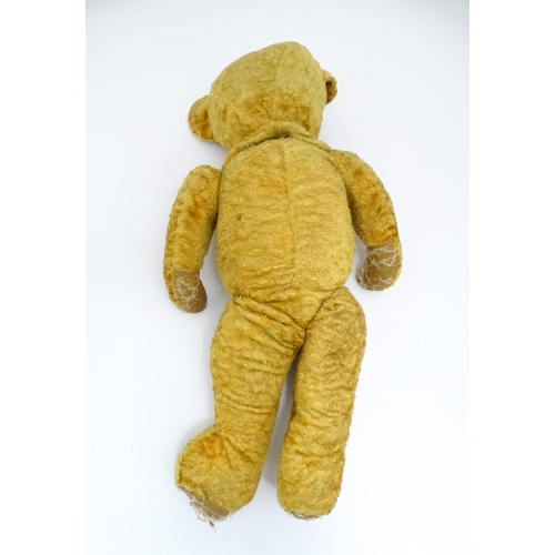 1426 - Toy: A large 20thC straw filled teddy bear with a stitched nose and mouth, and articulated limbs. Ap... 