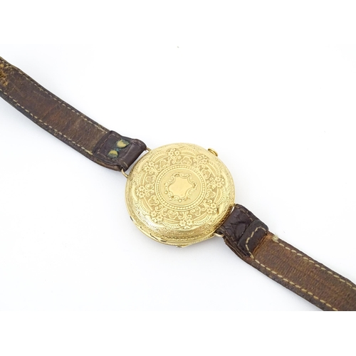 814 - An 18ct gold pocket watch converted into a wristwatch, with engraved floral and scroll detail. The d... 