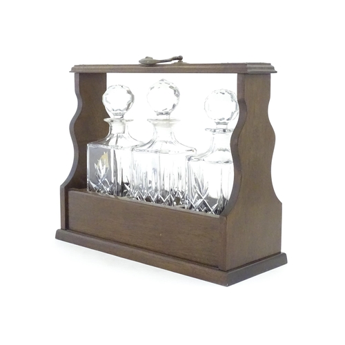 1211 - A 20thC mahogany tantalus with three cut glass decanters. Approx. 13