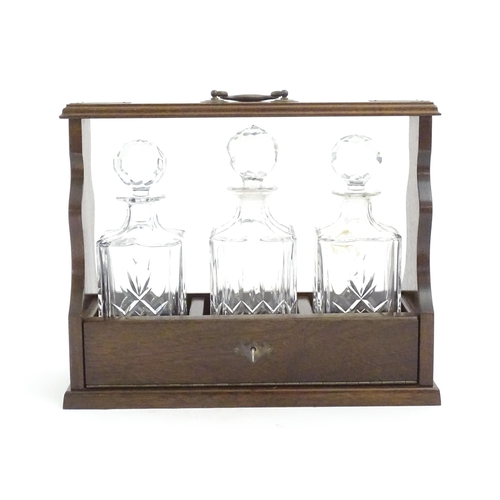 1211 - A 20thC mahogany tantalus with three cut glass decanters. Approx. 13