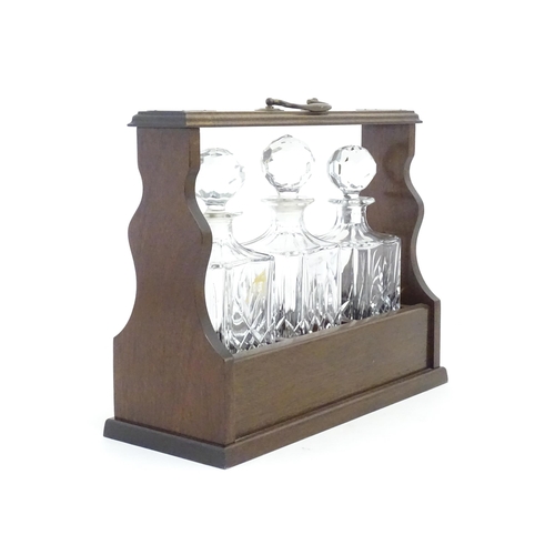 1211 - A 20thC mahogany tantalus with three cut glass decanters. Approx. 13