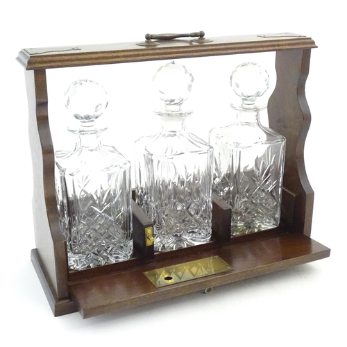 1211 - A 20thC mahogany tantalus with three cut glass decanters. Approx. 13