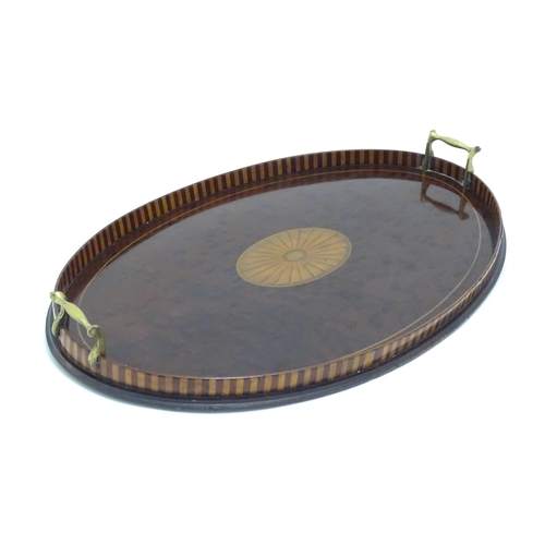 1319 - A 19thC mahogany tray of oval form with satinwood inlay and brass handles. Approx. 15 3/4