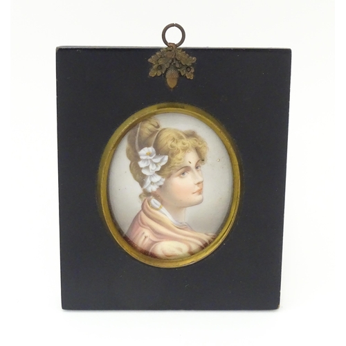 1266 - A 20thC oval watercolour and bodycolour portrait miniature depicting a young lady with flowers in he... 