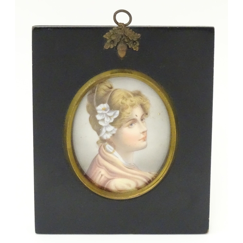 1266 - A 20thC oval watercolour and bodycolour portrait miniature depicting a young lady with flowers in he... 