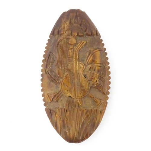 1286 - An 18thC carved nut snuff bottle with relief decoration depicting musical instruments and a portrait... 