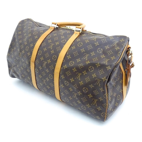 1399 - A Louis Vuitton Keepall 55 bag with shoulder strap and luggage label. Measures 21 3/4 x 12 1/4 x 9 1... 