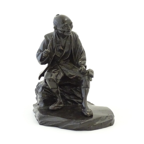 1148 - A Japanese cast sculpture modelled as a seated man on a rock smoking a kiseru pipe. Approx. 9 1/2