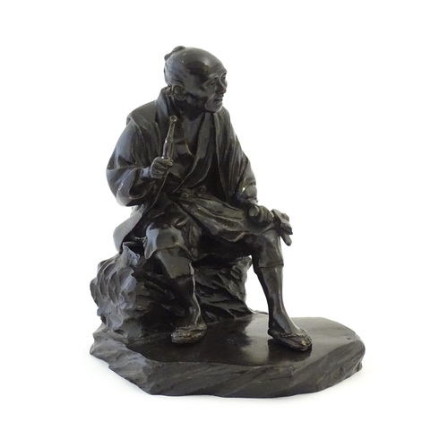 1148 - A Japanese cast sculpture modelled as a seated man on a rock smoking a kiseru pipe. Approx. 9 1/2