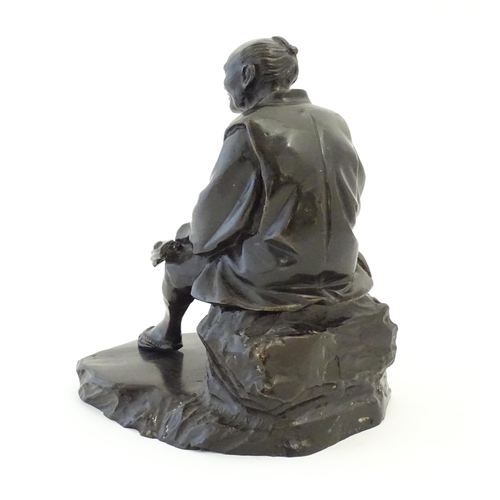 1148 - A Japanese cast sculpture modelled as a seated man on a rock smoking a kiseru pipe. Approx. 9 1/2