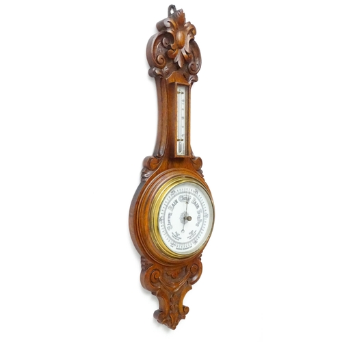 1550 - A 20thC aneroid barometer surmounted by thermometer within a carved wooden surround.  Approx. 30