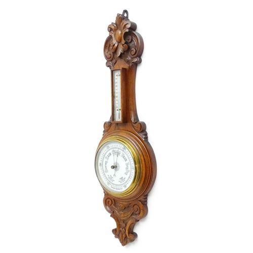 1550 - A 20thC aneroid barometer surmounted by thermometer within a carved wooden surround.  Approx. 30