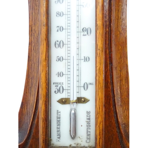 1550 - A 20thC aneroid barometer surmounted by thermometer within a carved wooden surround.  Approx. 30