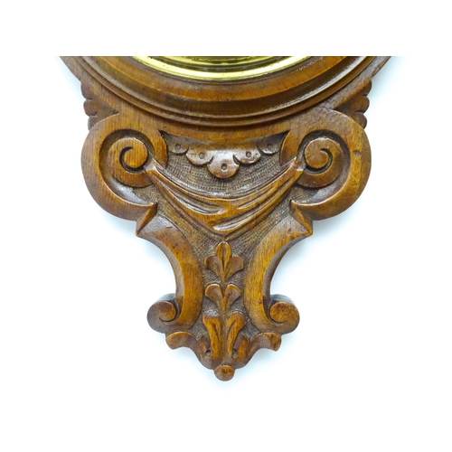 1550 - A 20thC aneroid barometer surmounted by thermometer within a carved wooden surround.  Approx. 30