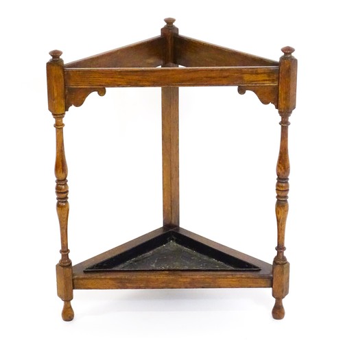 1669 - An early / mid 20thC oak stick / umbrella stand of triangular form, surmounted by finials and having... 