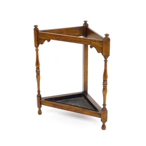 1669 - An early / mid 20thC oak stick / umbrella stand of triangular form, surmounted by finials and having... 