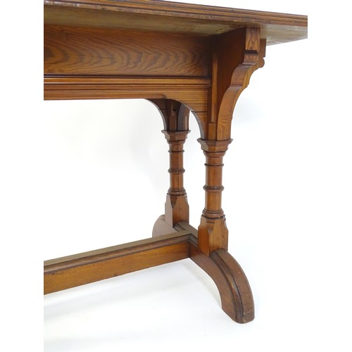 1602 - A late 19thC pine Gothic centre table, with a rectangular moulded top above four column formed taper... 