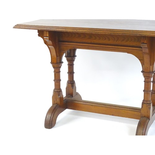 1602 - A late 19thC pine Gothic centre table, with a rectangular moulded top above four column formed taper... 