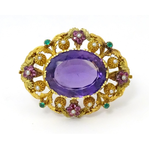 An impressive Victorian brooch set with large central amethyst within a floral and foliate mount set with rubies, seed pearls and emeralds. Approx 2" wide