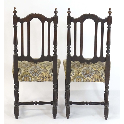 80 - A pair of late 19thC carved oak side chairs surmounted by turned finials and having carved cresting ... 