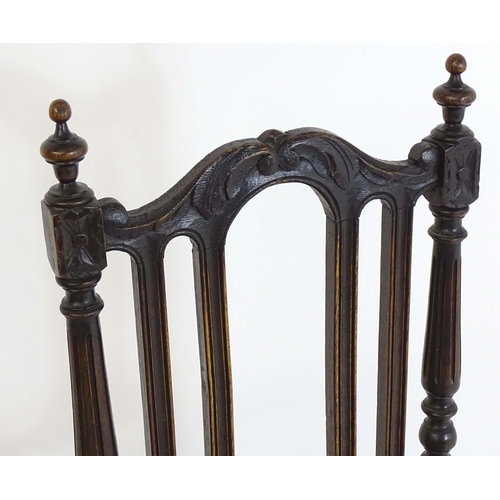 80 - A pair of late 19thC carved oak side chairs surmounted by turned finials and having carved cresting ... 