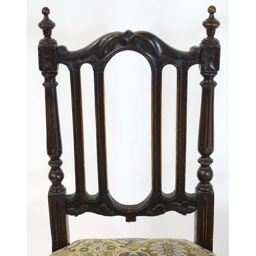 80 - A pair of late 19thC carved oak side chairs surmounted by turned finials and having carved cresting ... 