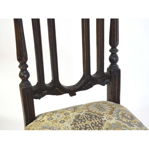 80 - A pair of late 19thC carved oak side chairs surmounted by turned finials and having carved cresting ... 