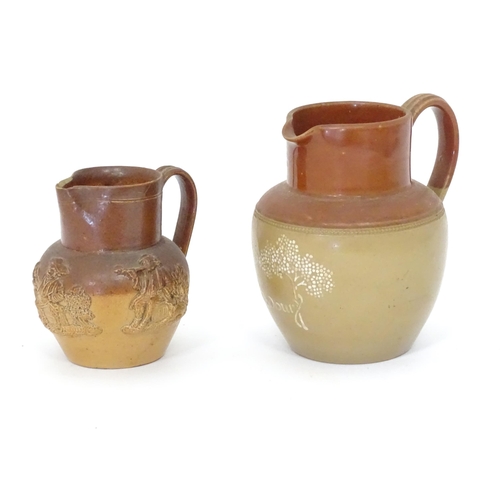 121 - A Doulton Lambeth two tone jug with relief decoration. Together with a two tone stoneware jug with C... 