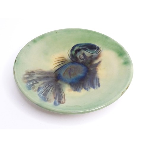 466 - A studio pottery plate with a green glaze decorated with a fish. Indistinctly marked under, possibly... 