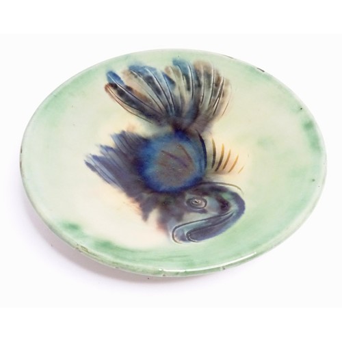 466 - A studio pottery plate with a green glaze decorated with a fish. Indistinctly marked under, possibly... 