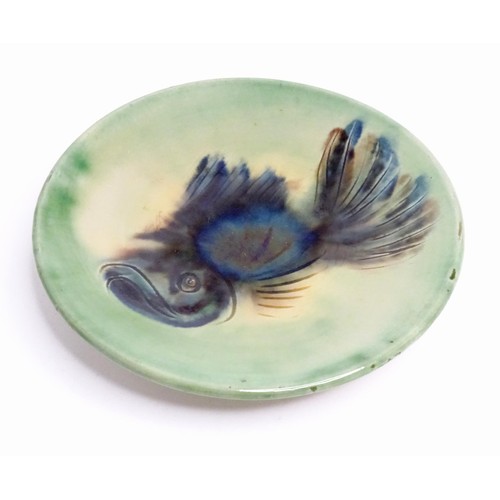 466 - A studio pottery plate with a green glaze decorated with a fish. Indistinctly marked under, possibly... 