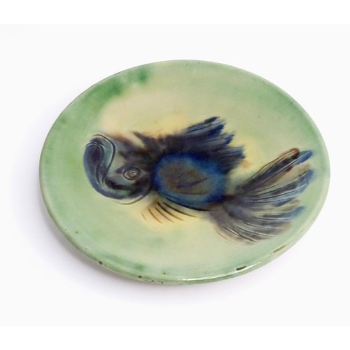 466 - A studio pottery plate with a green glaze decorated with a fish. Indistinctly marked under, possibly... 