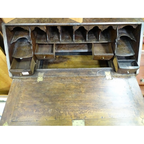 574 - An 18thC oak bureau with fall front over two short over two long drawers with swan neck handles. The... 