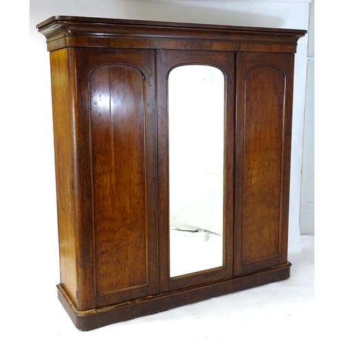 100 - A Victorian mahogany triple wardrobe with a moulded cornice above a central mirrored door and two ar... 