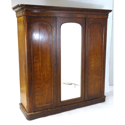 100 - A Victorian mahogany triple wardrobe with a moulded cornice above a central mirrored door and two ar... 