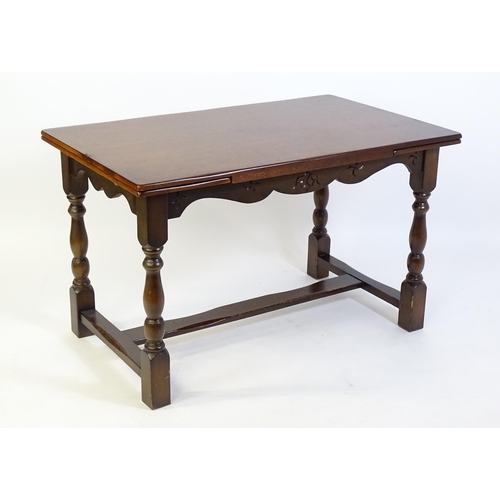 522 - A mid 20thC draw leaf dining table, with four block and turned legs united by a H - stretcher. 48