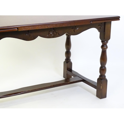 522 - A mid 20thC draw leaf dining table, with four block and turned legs united by a H - stretcher. 48